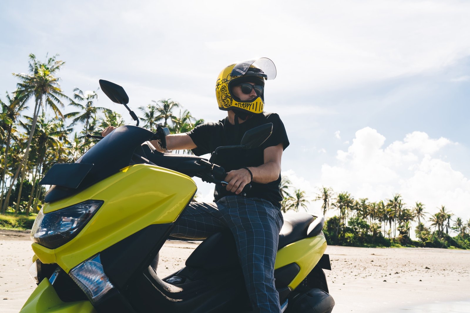Rider on stylish motorcycle looking away on tropical background